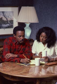 Young African American couple seated at table looking over documents